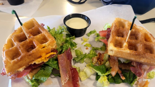 Two waffle sandwiches filled with bacon, lettuce, and tomato, served with a side of ranch dressing.